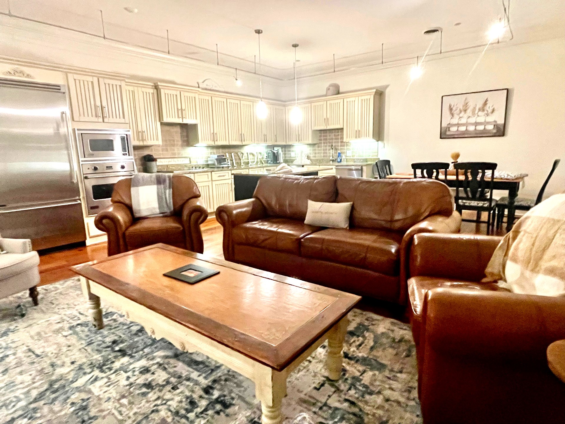Wide view of the open living and kitchen with leather seating and tall ceilings