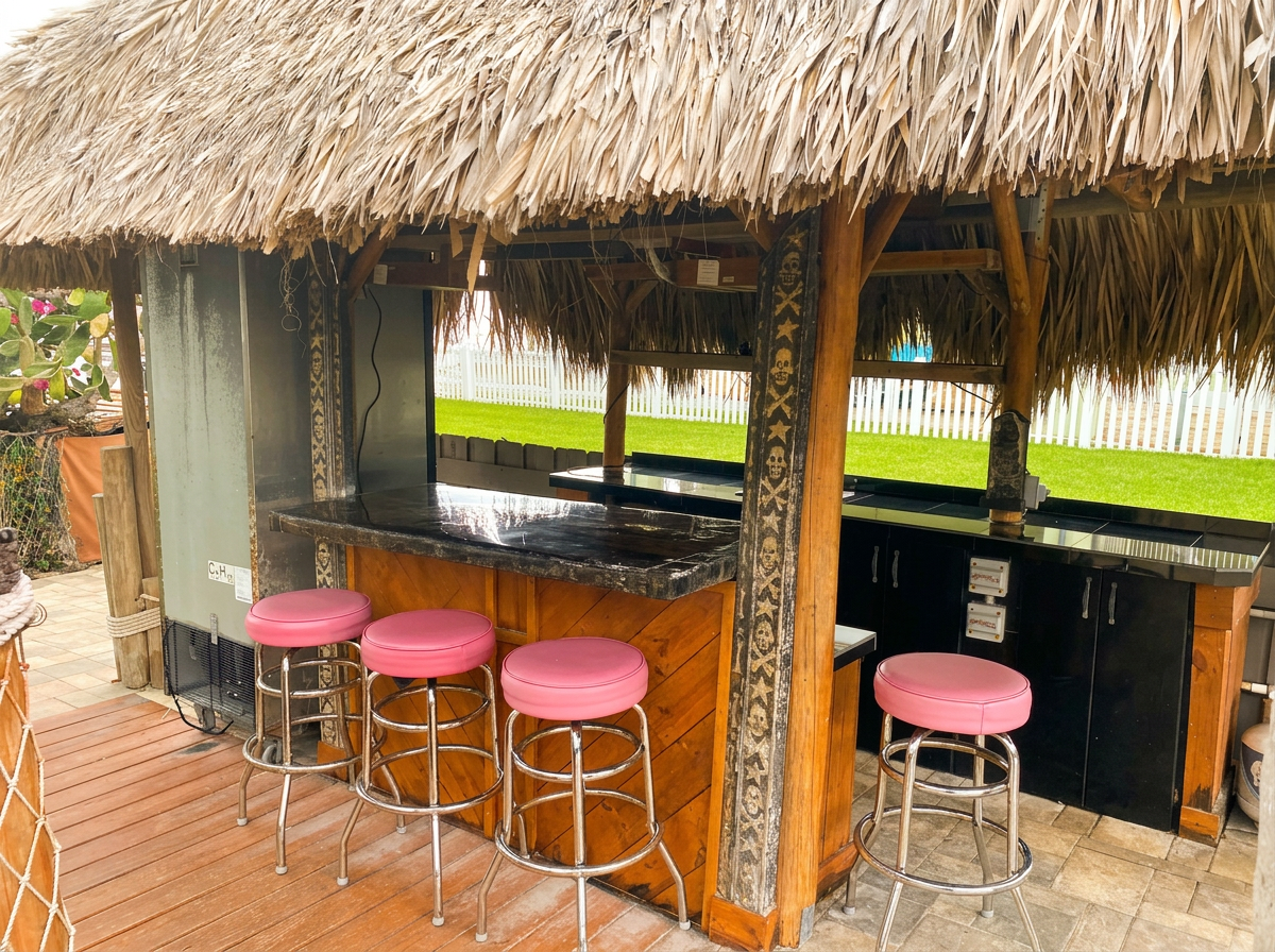 Backyard tiki hut bar with thatched roof and bar seating